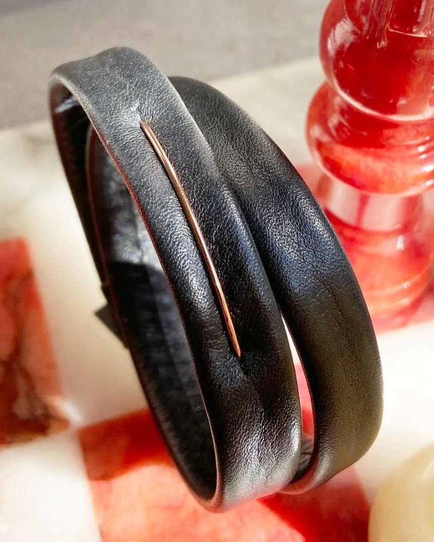Bracciale a fascia in pelle nera con un sottile filo d’oro rosa al centro